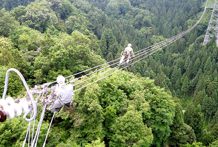 鉄塔から伸びる電線の上で作業する皆様